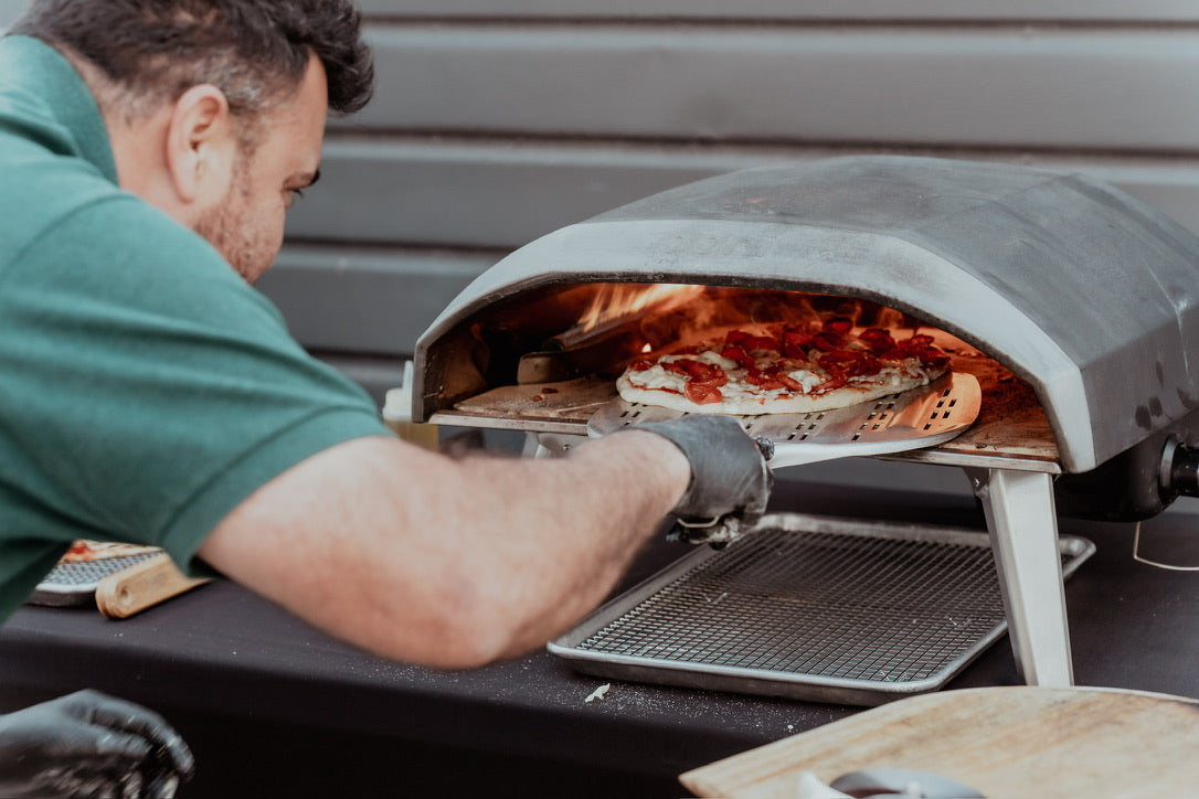 Man pulling pizza out of pizza oven